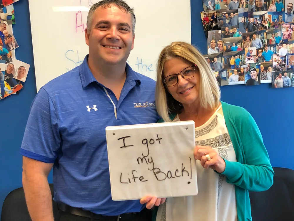 Dr. Nathan Weiss with a smiling patient holding an "I got my life back!" sign at True North Chiropractic Center in Thief River Falls, MN